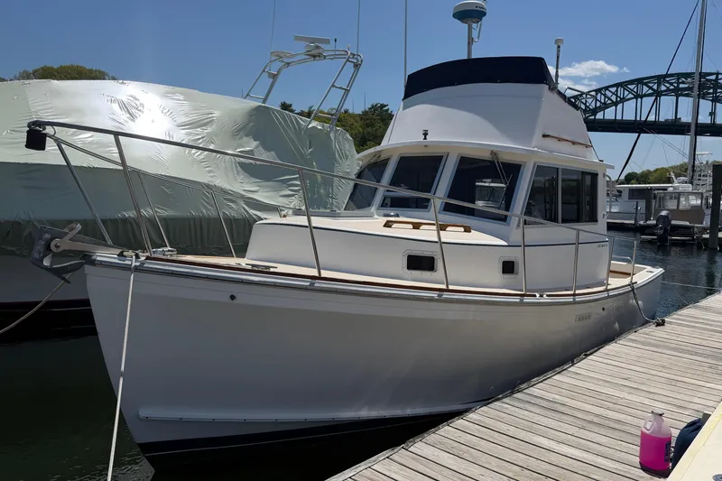 Slide: The Image of 1990 Cape Dory 28 Flybridge boat docked at marina under clear sky. - 16
