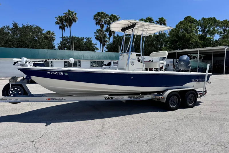 The Image of 2012 Pathfinder 2200 TRS boat on trailer, parked outdoors under clear blue sky. - 4