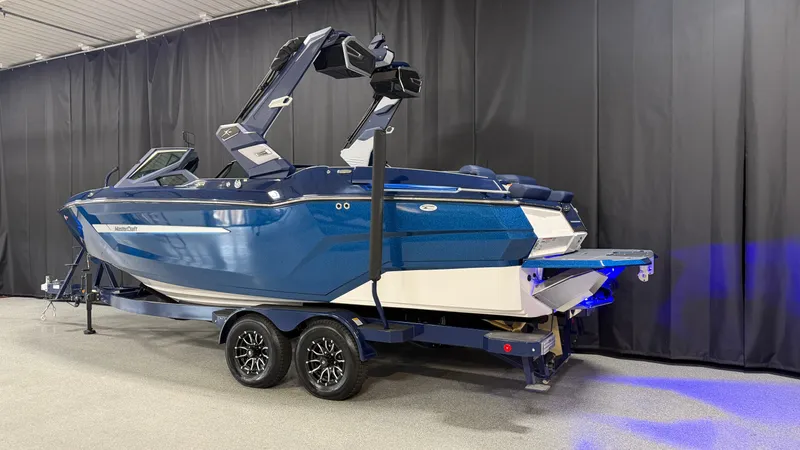 Slide: The Image of A blue 2027 MasterCraft XT23 on a trailer in a showroom setting. - 3