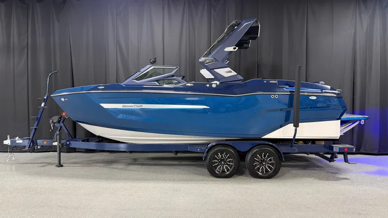 Slide: The Image of The image shows a blue 2027 MasterCraft XT23 boat on a trailer. - 0
