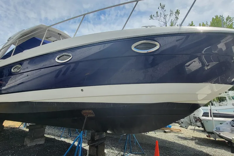 The Image of 2008 Monterey 350 Sport Yacht on stands, blue and white hull, outdoor setting. - 0