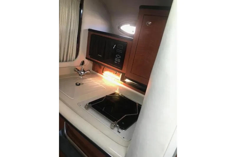 Slide: The Image of 2004 Sea Ray Sundancer 280 interior kitchen with sink, stove, and microwave. - 17