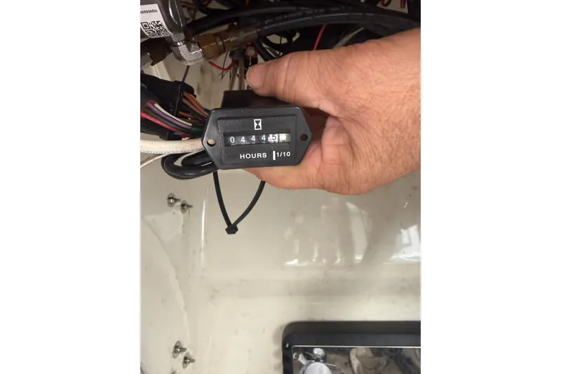 Slide: The Image of Hand holding hour meter showing 44.5 hours on a 2015 Mako 19 CPX boat. - 12