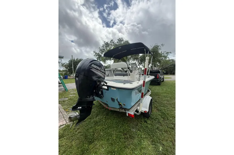 Slide: The Image of 2015 Mako 19 CPX boat with Mercury engine on trailer, parked on grass. - 3