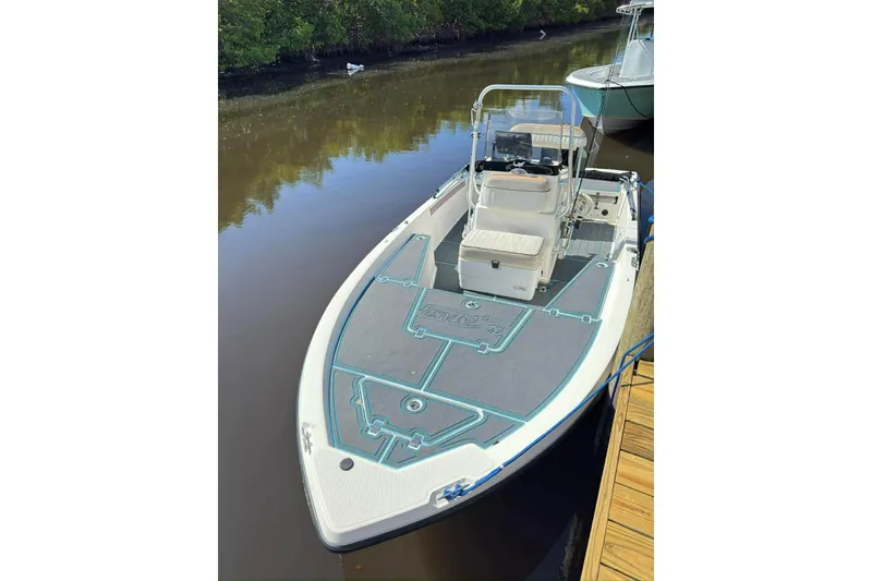 Slide: The Image of 2015 Mako 19 CPX boat docked on calm water, featuring a spacious deck. - 4