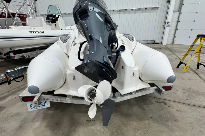The Image of 2021 Zodiac Yachtline 440 inflatable boat with outboard motor in a garage setting. - 1