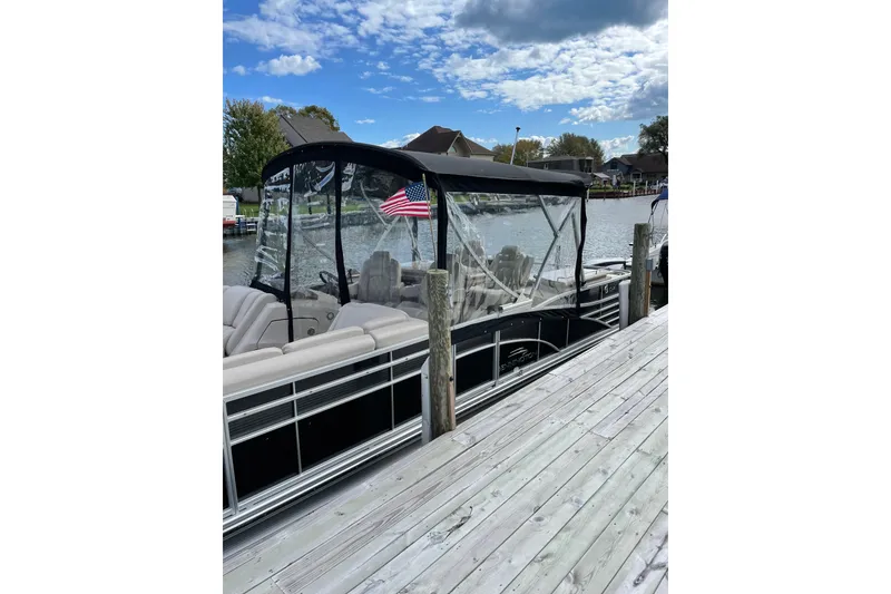 Slide: The Image of 2015 Bennington 2575 QSD pontoon boat docked by a wooden pier, under a partly cloudy sky. - 18