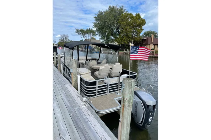 Slide: The Image of 2015 Bennington 2575 QSD pontoon boat docked with American flag and outboard motor. - 20