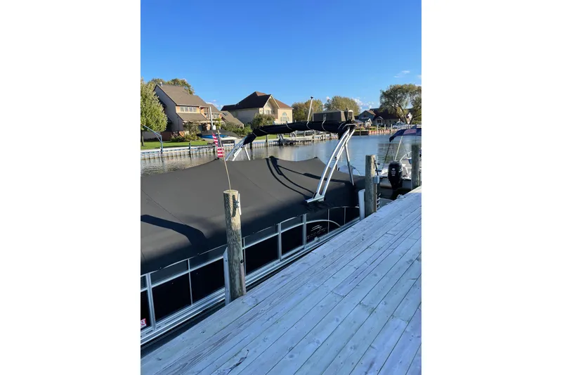 Slide: The Image of 2015 Bennington 2575 QSD pontoon boat docked by waterfront homes. - 7