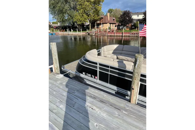 Slide: The Image of 2015 Bennington 2575 QSD pontoon boat docked by a wooden pier with American flag. - 9