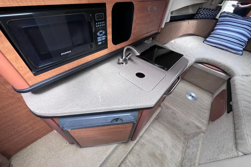 Slide: The Image of 2006 Sea Ray Sundancer 260 cabin interior with kitchenette, microwave, and cozy seating area. - 14