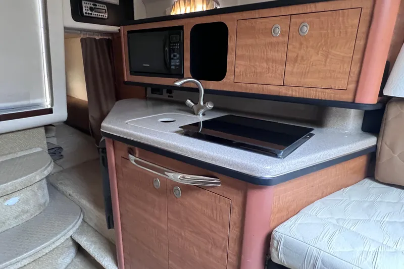 Slide: The Image of 2006 Sea Ray Sundancer 260 interior kitchen with sink, microwave, and storage cabinets. - 16