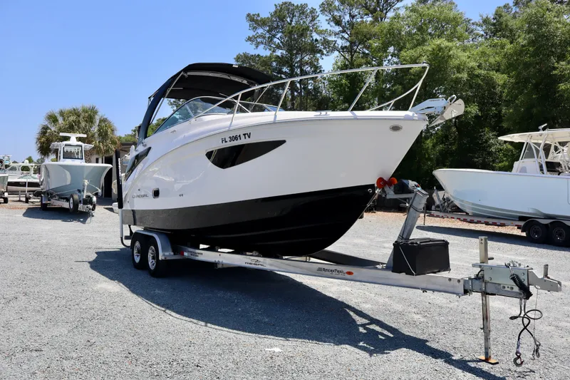 Slide: The Image of 2023 Regal 26 XO boat on trailer, parked outdoors with trees in background. - 3