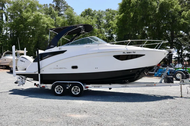Slide: The Image of 2023 Regal 26 XO boat on trailer, parked outdoors with trees in background. - 4
