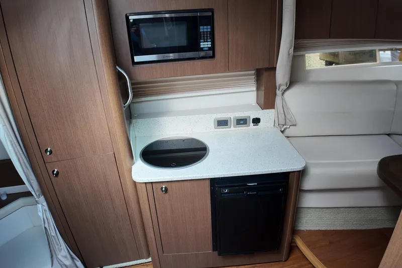 Slide: The Image of 2015 Sea Ray 370 Venture interior kitchen with microwave, stove, and compact fridge. - 8