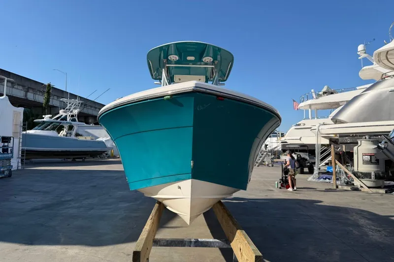 Slide: The Image of 2018 Cobia 220 Center Console boat in a marina, vibrant blue hull, clear sky background. - 2