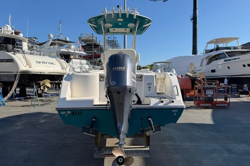 Slide: The Image of 2018 Cobia 220 Center Console boat with 200 HP engine in a marina setting. - 5
