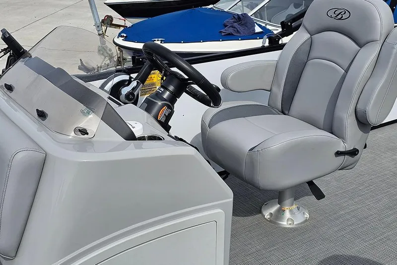 Slide: The Image of 2026 Bentley Pontoons 243 FNC helm with plush captain's chair and steering console. - 21