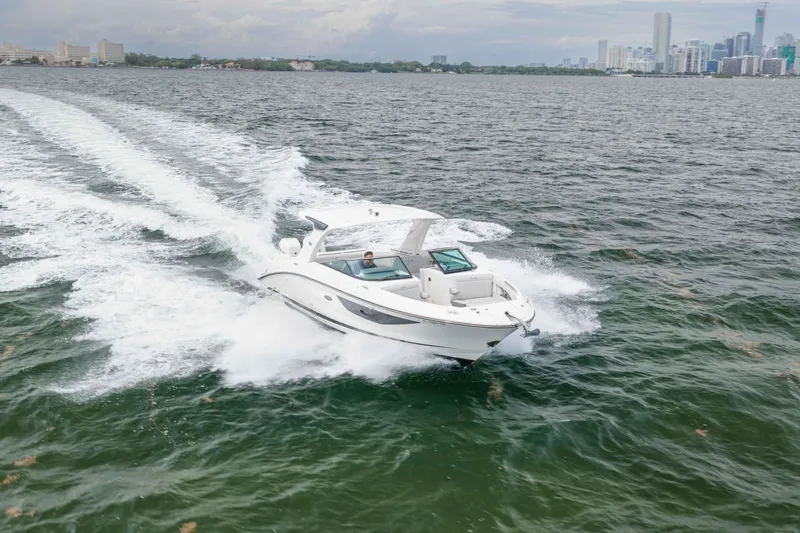 Slide: The Image of 2023 Sea Ray SLX 350 Outboard cruising on open water near city skyline. - 21