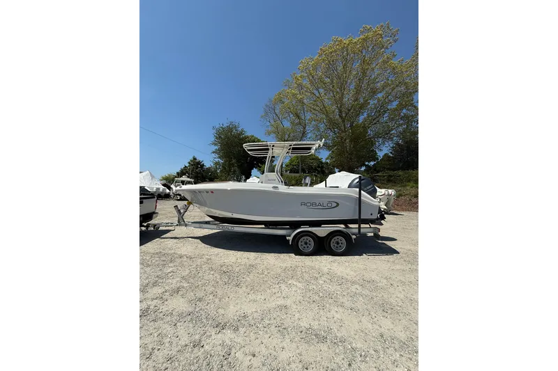 The Image of 2023 Robalo R202 Explorer boat on trailer, parked outdoors under clear blue sky. - 0