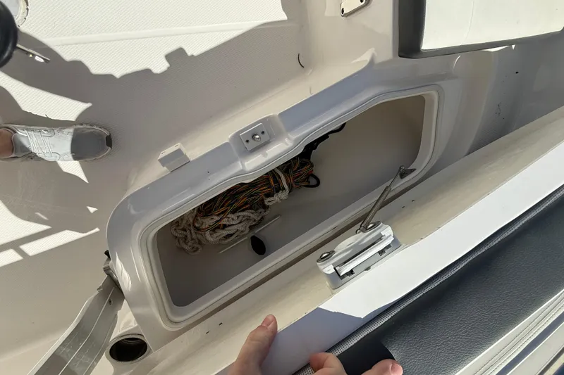 Slide: The Image of 2023 Robalo R202 Explorer boat storage compartment with ropes and latch mechanism. - 15