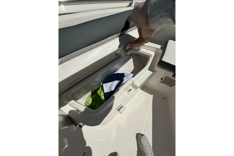 Slide: The Image of 2023 Robalo R202 Explorer boat storage compartment with towels inside. - 18