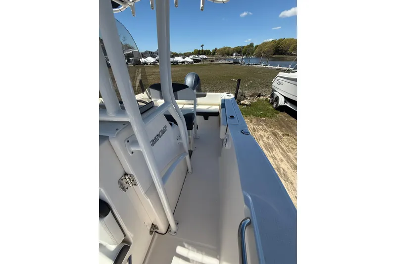 Slide: The Image of 2023 Robalo R202 Explorer boat interior with seating, docked near a grassy shore. - 23