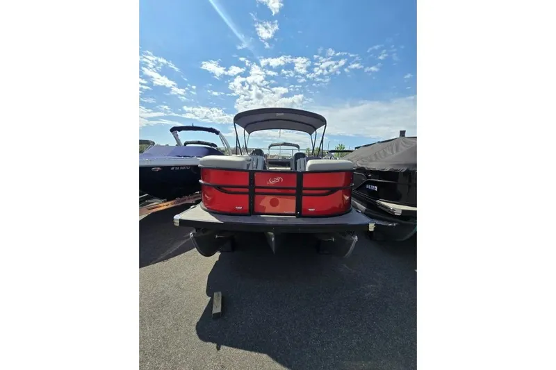Slide: The Image of 2024 Barletta C22UC pontoon boat, red exterior, parked under a clear blue sky. - 2