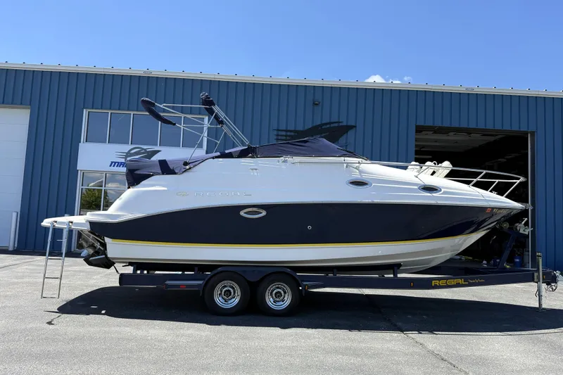 Slide: The Image of 2005 Regal Commodore 2665 boat on trailer, parked outside a blue building. - 1