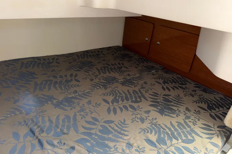 Slide: The Image of Interior cabin of 2005 Regal Commodore 2665 with floral-patterned bedding and wooden storage. - 16