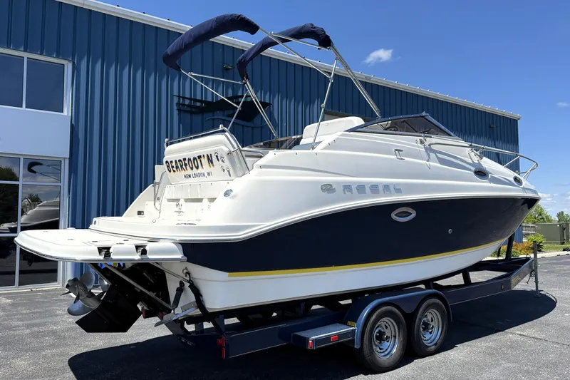 Slide: The Image of 2005 Regal Commodore 2665 boat on trailer, parked outside blue building. - 2