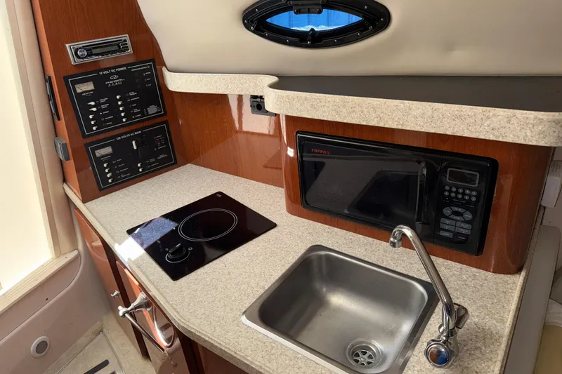 Slide: The Image of Compact kitchen area in a 2005 Regal Commodore 2665 boat with sink, stove, and microwave. - 21