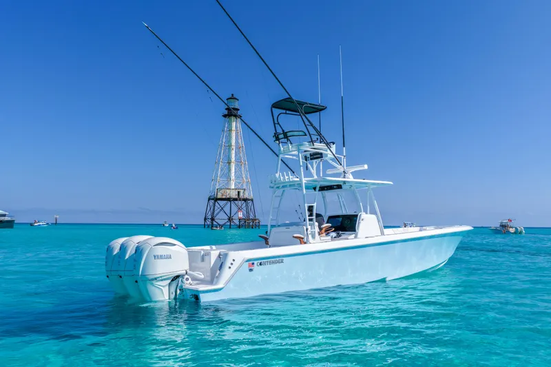Slide: The Image of 2026 Contender 39 ST boat on clear blue water near a lighthouse. - 2