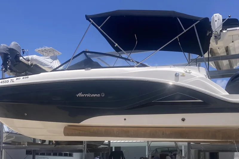 The Image of 2023 Hurricane SunDeck 235 OB boat with black canopy, docked under clear blue sky. - 0