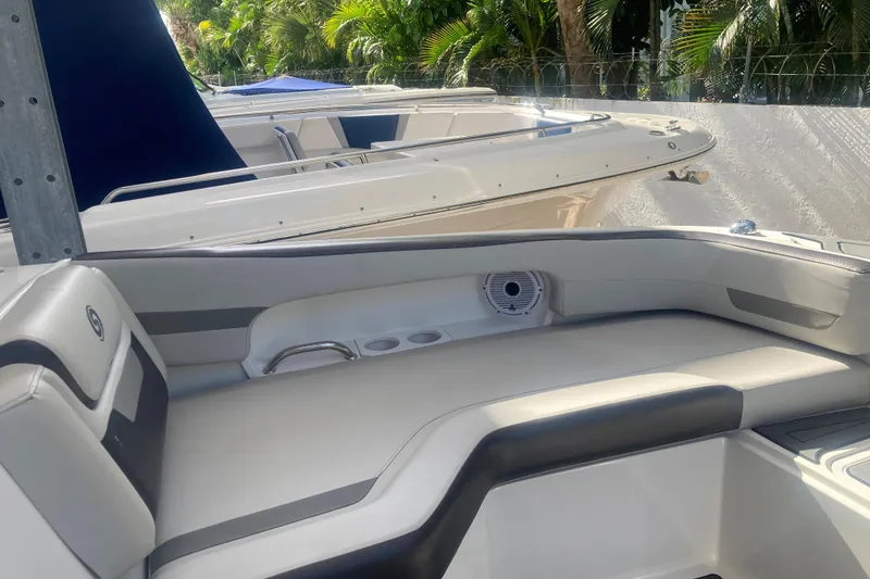 Slide: The Image of 2023 Hurricane SunDeck 235 OB boat interior with cushioned seating and speaker, surrounded by greenery. - 9