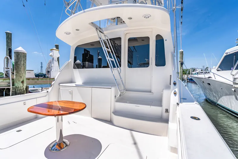 Slide: The Image of The 2004 Ocean Yachts 50 Convertible is docked. It features a spacious aft deck with a wooden table. - 13