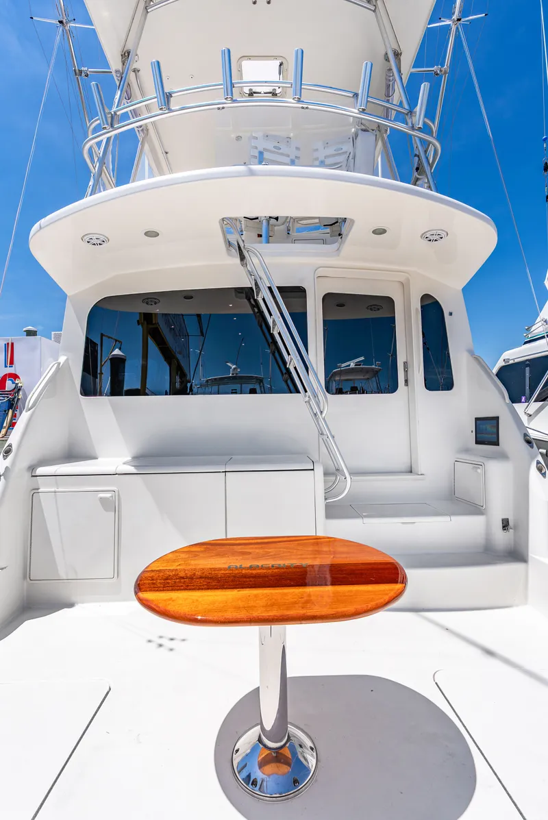 Slide: The Image of The image shows the stern of a 2004 Ocean Yachts 50 Convertible with a glossy wooden table. - 18