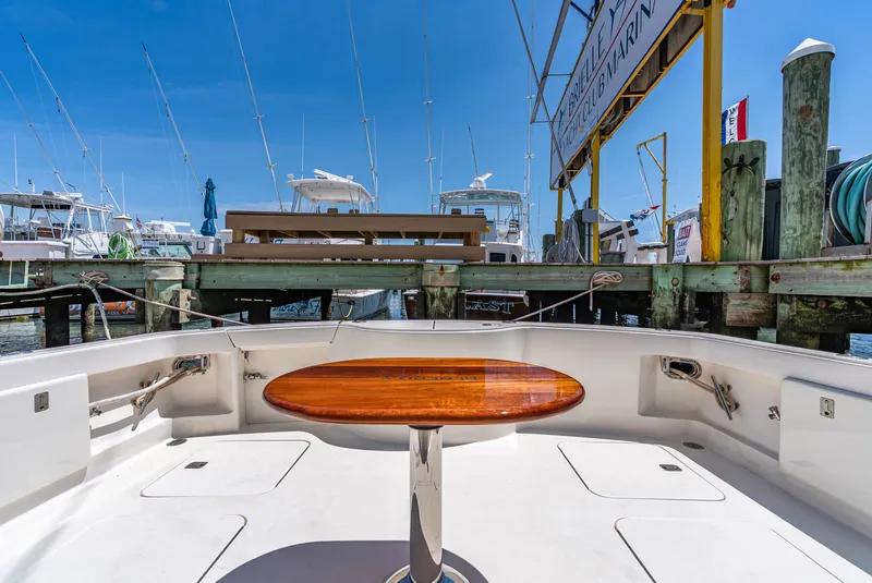 Slide: The Image of The image shows the cockpit of a 2004 Ocean Yachts 50 Convertible. It features a wooden table and is surrounded by a marina with several boats. - 22