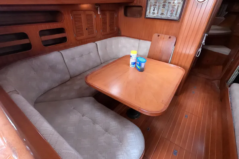 Slide: The Image of Cozy dining area in 1986 Ta Shing Baba 40 sailboat with wooden table and cushioned seating. - 15