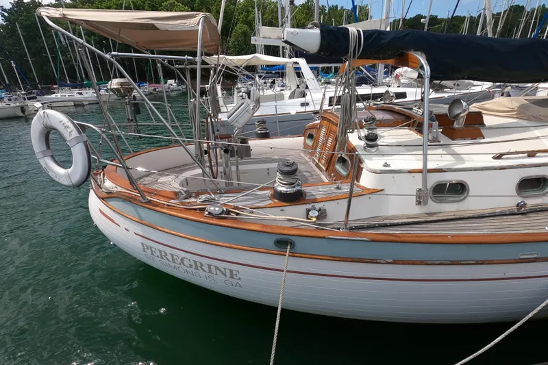 Slide: The Image of 1986 Ta Shing Baba 40 sailboat docked, featuring wooden accents and lifebuoy. - 2