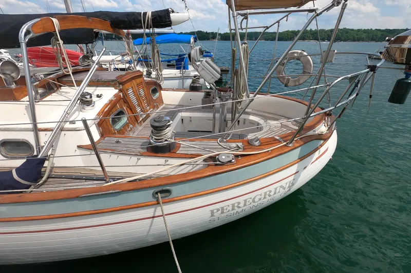 Slide: The Image of 1986 Ta Shing Baba 40 sailboat docked on calm water, featuring wooden deck and classic design. - 5