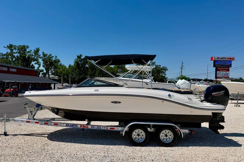 The Image of 2022 Sea Ray SPX 210 Outboard boat on trailer, displayed outdoors under clear blue sky. - 0