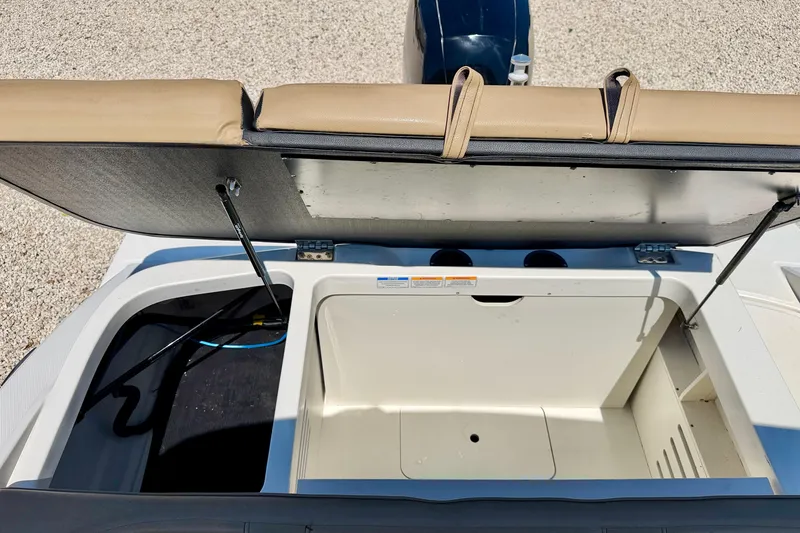 Slide: The Image of 2022 Sea Ray SPX 210 Outboard boat storage compartment with open lid and beige seating. - 27