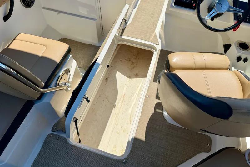 Slide: The Image of 2022 Sea Ray SPX 210 Outboard interior with open storage compartment and beige seating. - 28