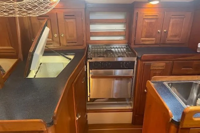 Slide: The Image of 2001 Tartan 3700 yacht kitchen with wooden cabinets, stove, and sink. - 10