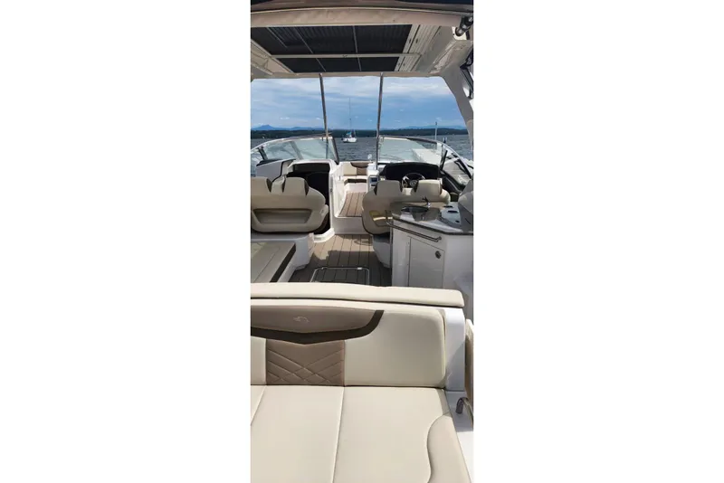 Slide: The Image of 2023 Chaparral 347 SSX boat interior with luxurious seating and helm, cruising on open water. - 10