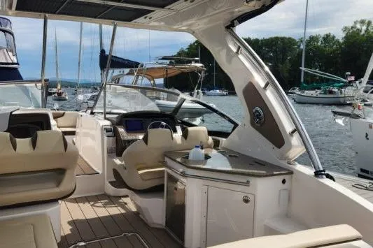 Slide: The Image of 2023 Chaparral 347 SSX boat interior with luxurious seating and helm, docked in a marina. - 4