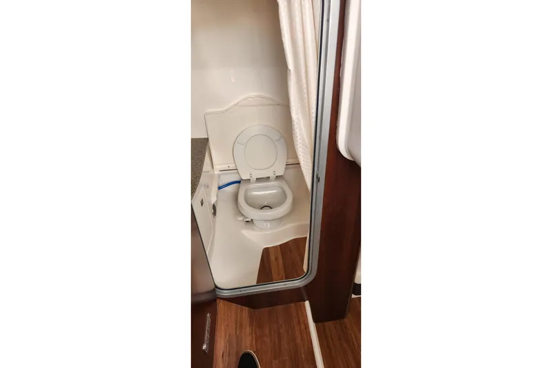 Slide: The Image of 2023 Chaparral 347 SSX boat bathroom interior with toilet and wooden flooring. - 9