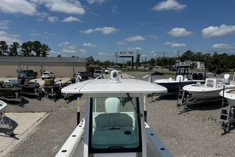 Slide: The Image of 2020 Everglades 253 Center Console boat displayed outdoors with other boats and vehicles. - 1