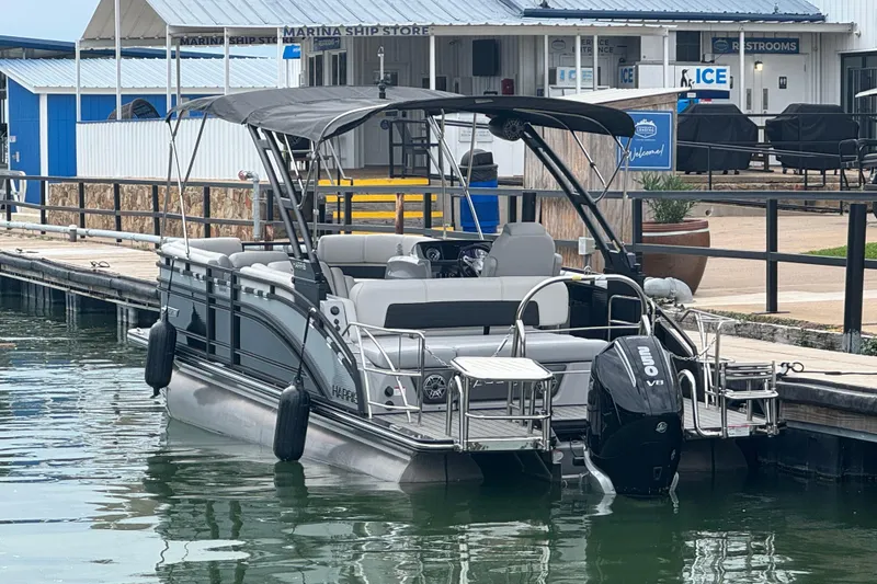 The Image of 2023 Harris Solstice 230 pontoon boat docked at marina with Mercury V8 engine. - 1